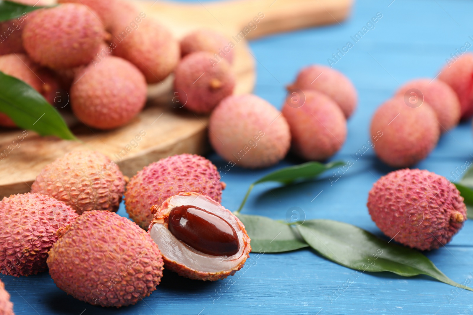 Photo of Fresh ripe lychee fruits on blue wooden table