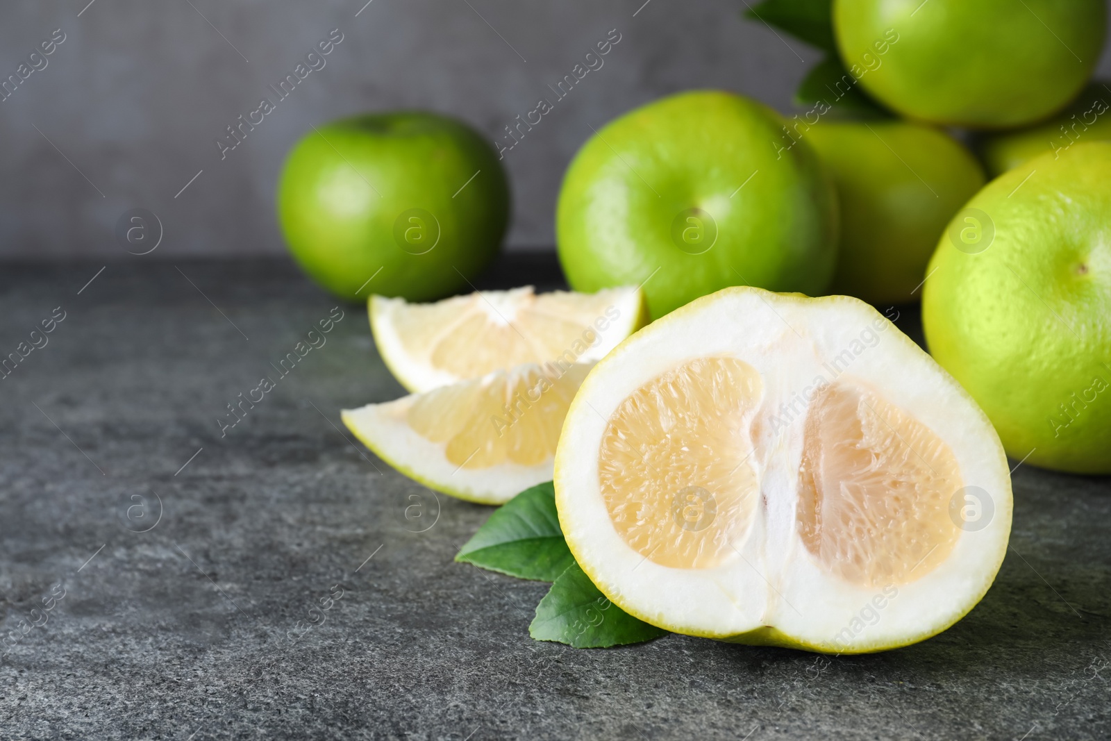 Photo of Cut and whole fresh sweeties on grey table, space for text