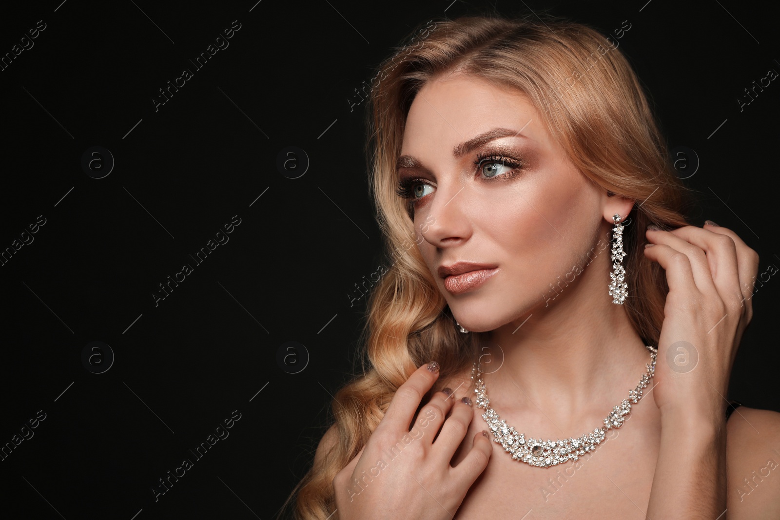 Photo of Beautiful young woman with elegant jewelry on dark background. Space for text