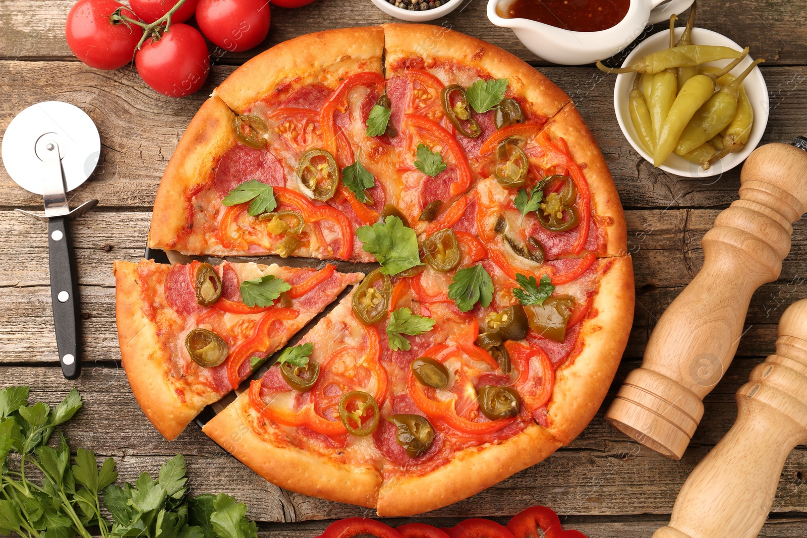 Photo of Delicious pizza Diablo, ingredients and cutter on wooden table, flat lay