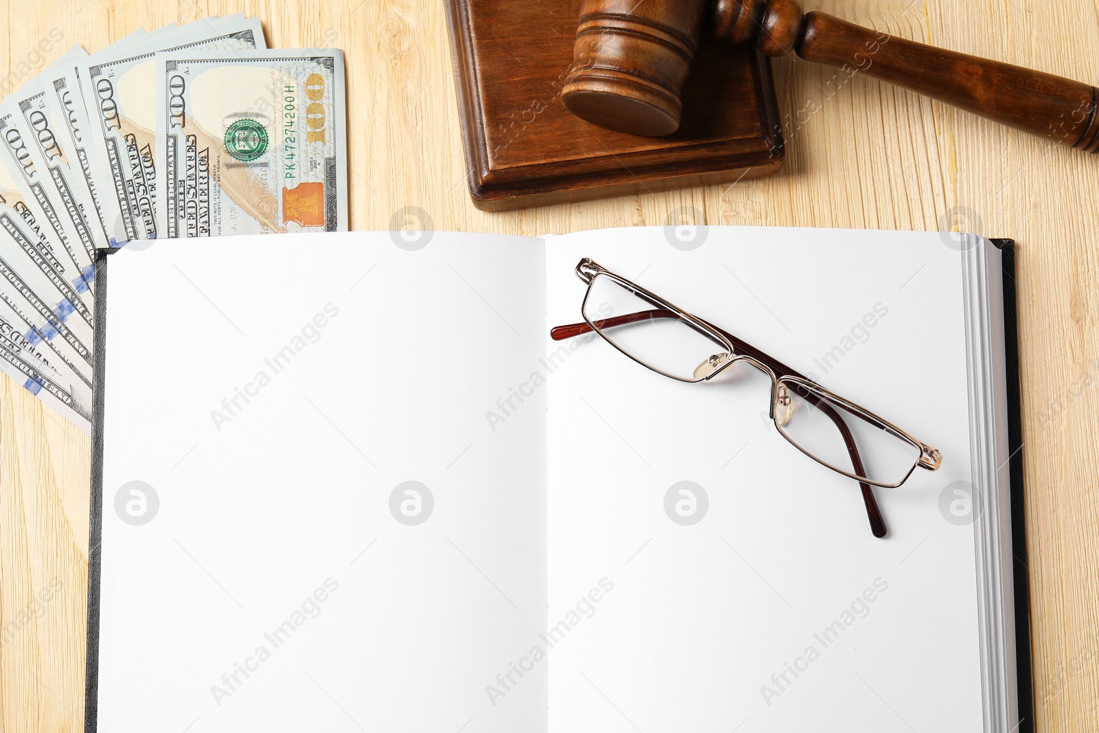 Photo of Tax law. Notebook, gavel, dollar banknotes and glasses on wooden table, flat lay