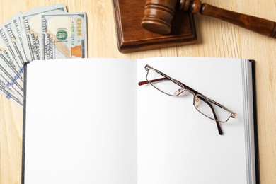 Tax law. Notebook, gavel, dollar banknotes and glasses on wooden table, flat lay