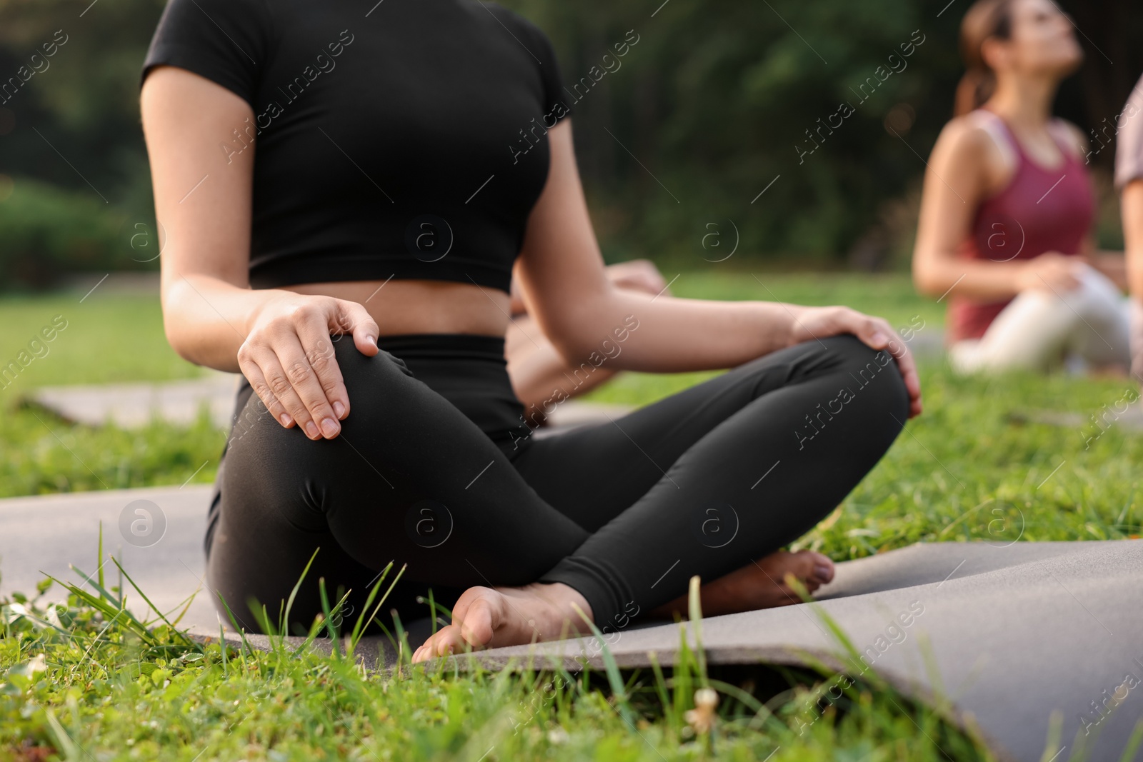 Photo of People practicing yoga in park outdoors, closeup. Lotus pose