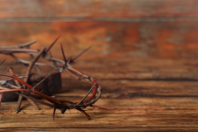 Photo of Crown of thorns and hammer on wooden table, closeup with space for text. Easter attributes