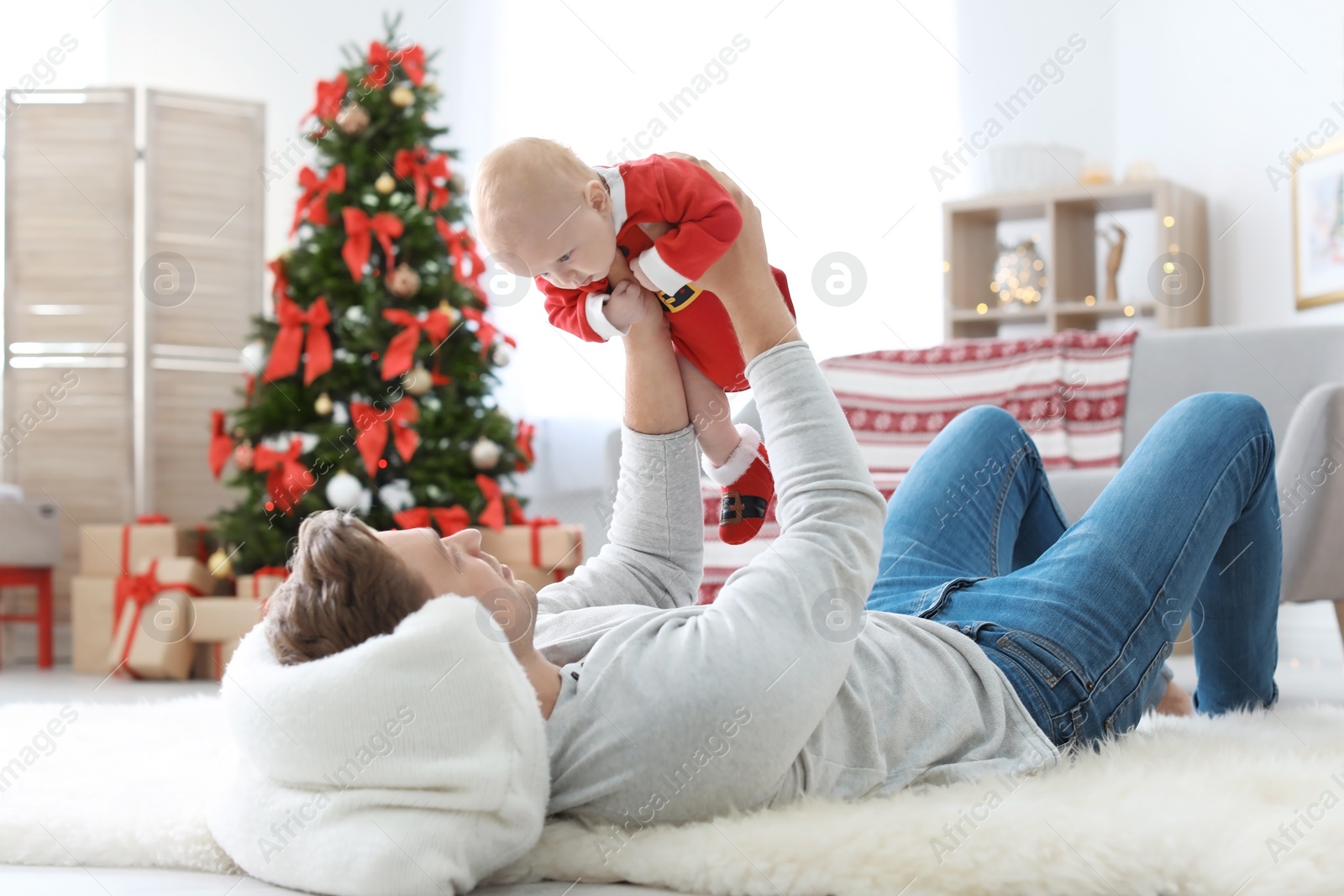 Photo of Young man with baby in Christmas suit at home