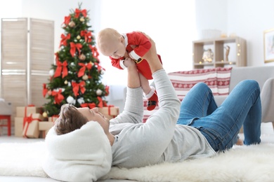 Young man with baby in Christmas suit at home