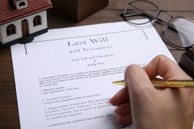 Photo of Woman signing last will and testament at table, closeup