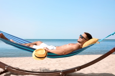 Photo of Young man relaxing in hammock on beach