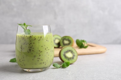 Delicious kiwi smoothie and fresh ingredients on light grey table, space for text