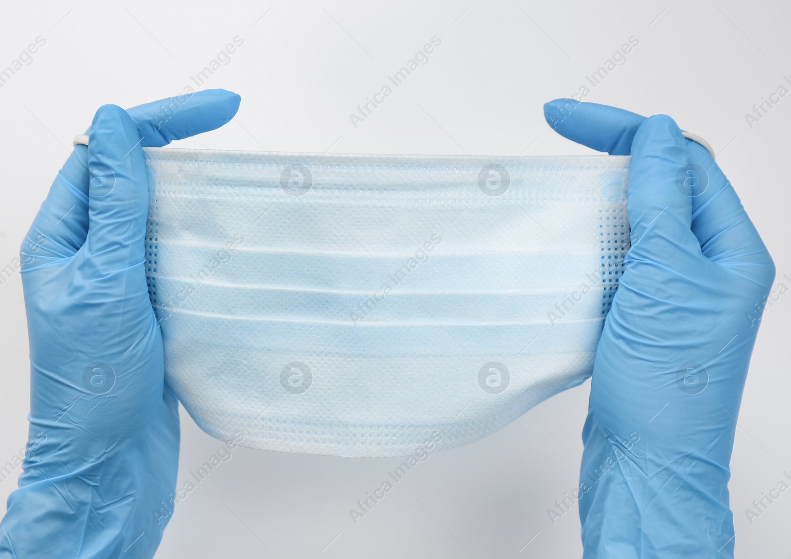 Photo of Doctor in medical gloves holding protective mask on white background, closeup