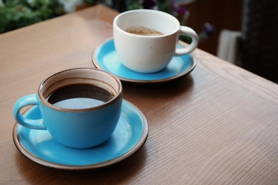 Cups of fresh aromatic coffee on wooden table