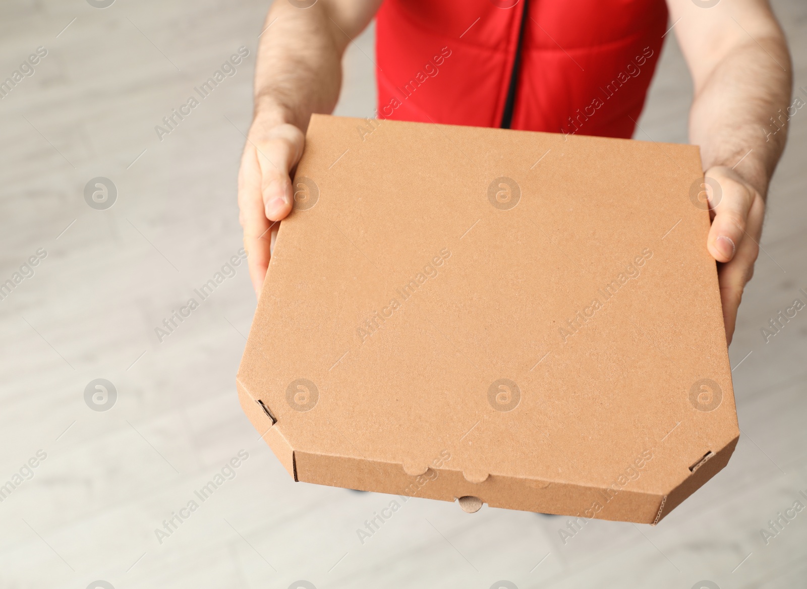 Photo of Man with pizza box indoors, closeup. Food delivery service