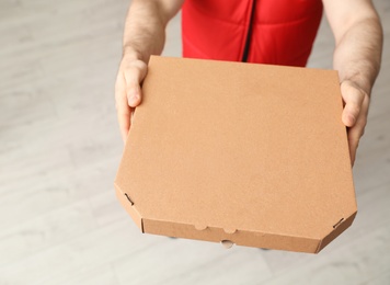 Photo of Man with pizza box indoors, closeup. Food delivery service