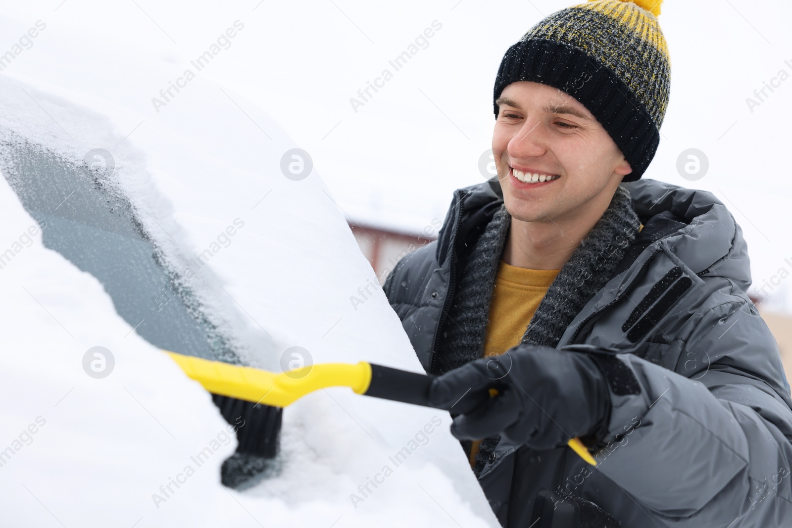 Photo of Man cleaning snow from car windshield outdoors