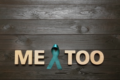 Phrase Me Too made of letters and teal awareness ribbon on wooden background, top view. Stop sexual assault