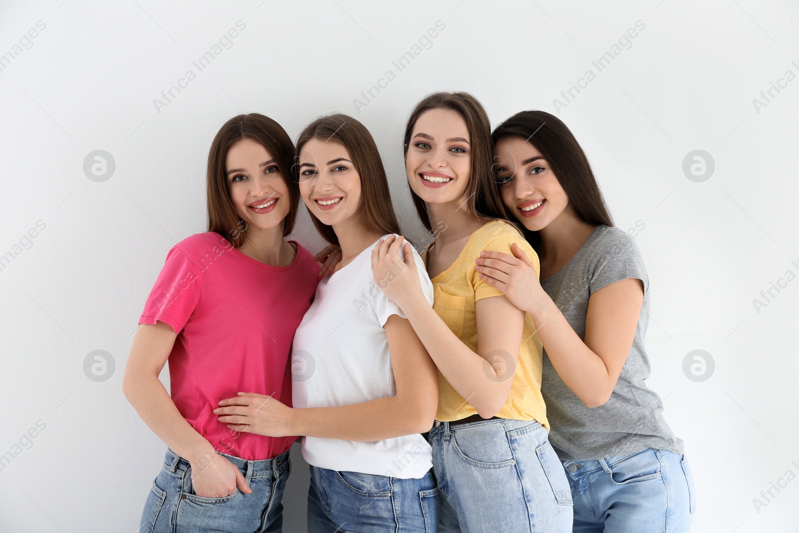 Photo of Beautiful young ladies in jeans and colorful t-shirts on white background. Woman's Day