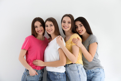 Photo of Beautiful young ladies in jeans and colorful t-shirts on white background. Woman's Day