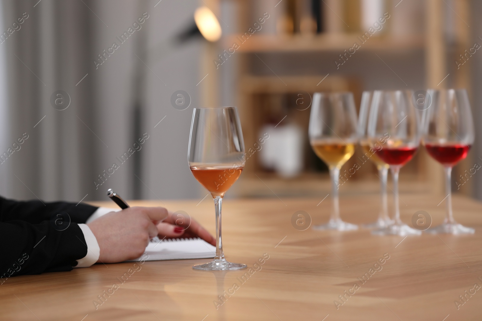 Photo of Sommelier making notes during wine tasting at table indoors, closeup