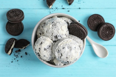 Flat lay composition with bowl of ice cream and crumbled chocolate cookies on wooden background