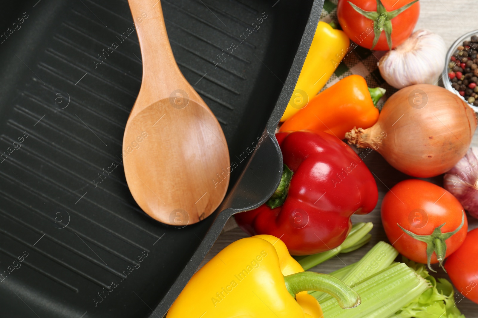 Photo of Black pot, wooden spoon and fresh products on table, top view