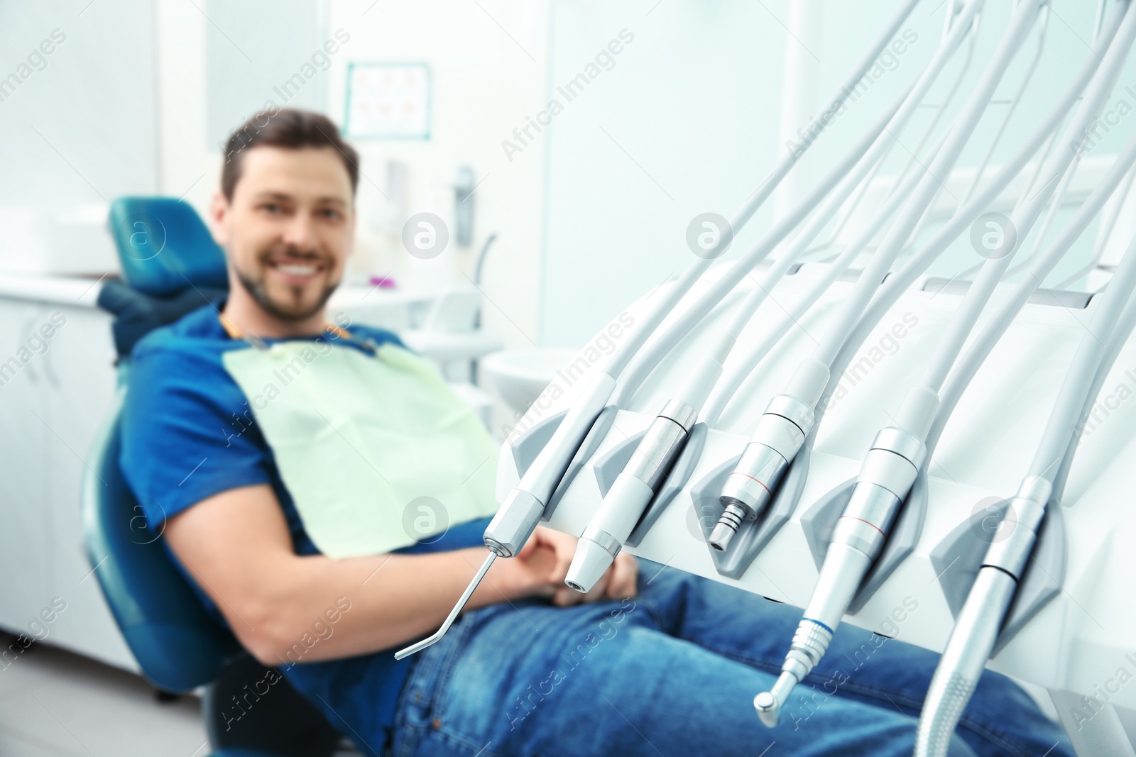 Photo of Set of professional instruments and happy patient in dentist's office