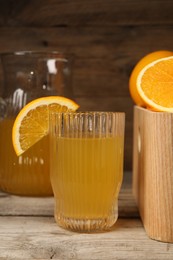 Many ripe oranges and fresh juice on wooden table