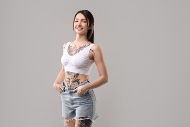 Photo of Portrait of smiling tattooed woman on grey background