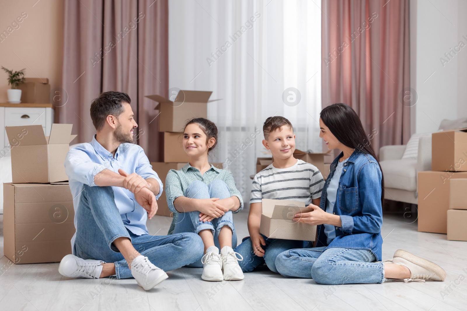 Photo of Happy family settling into new house and unpacking boxes on floor. Moving day