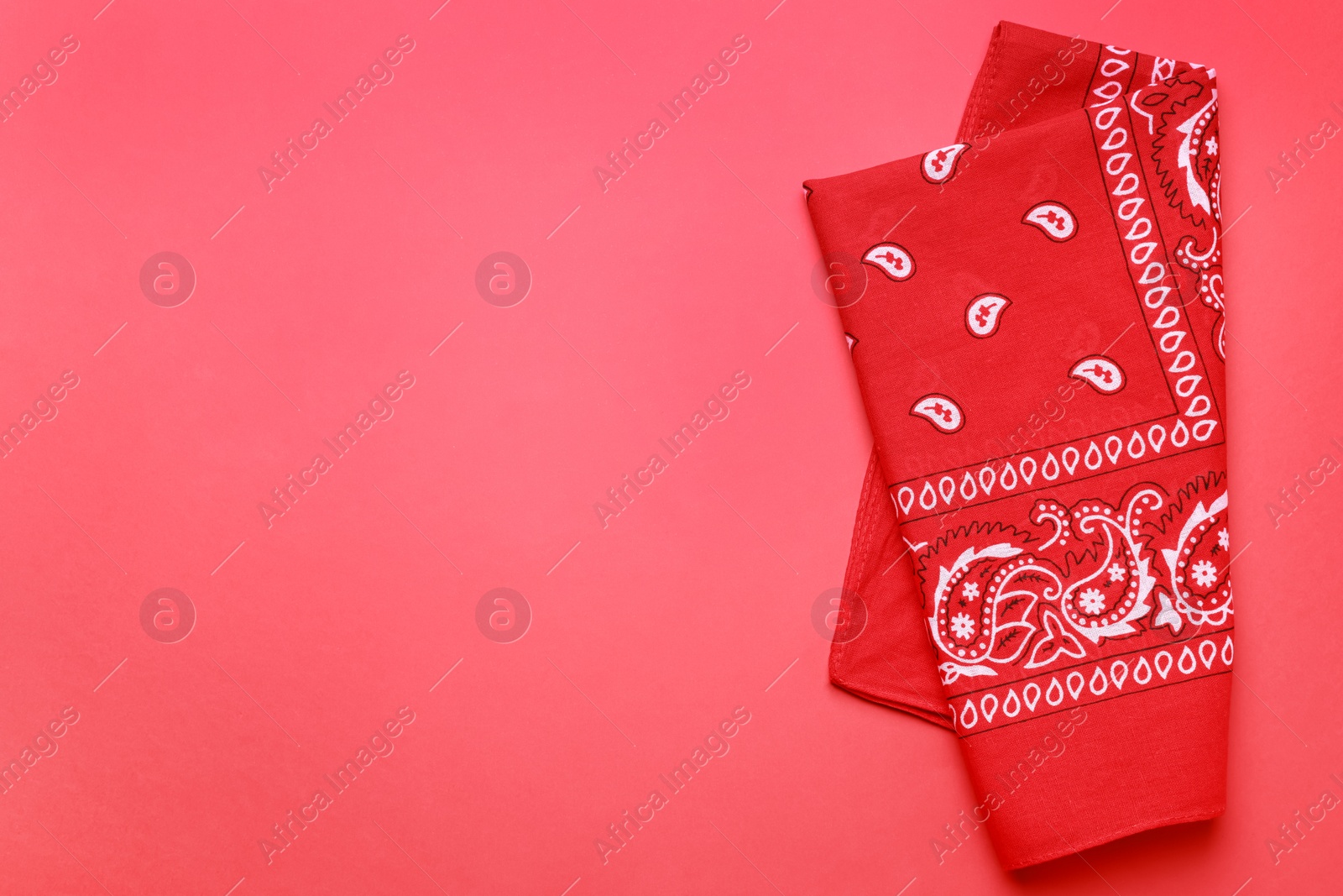 Photo of Folded bandana with paisley pattern on red background, top view. Space for text