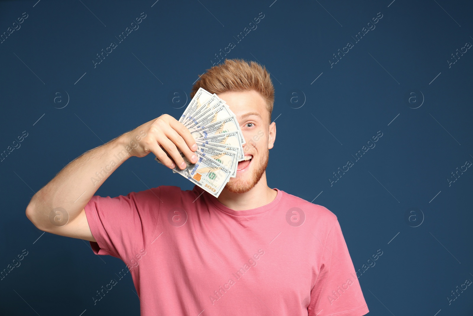 Photo of Portrait of happy lottery winner with money fan on blue background