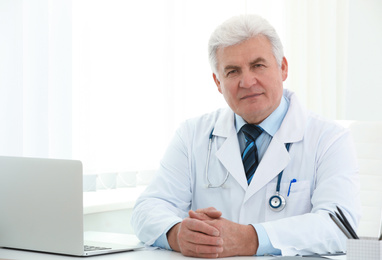 Portrait of senior doctor in white coat at workplace