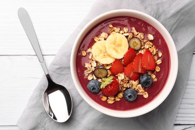 Photo of Delicious smoothie bowl with fresh berries, banana and granola on white wooden table, flat lay