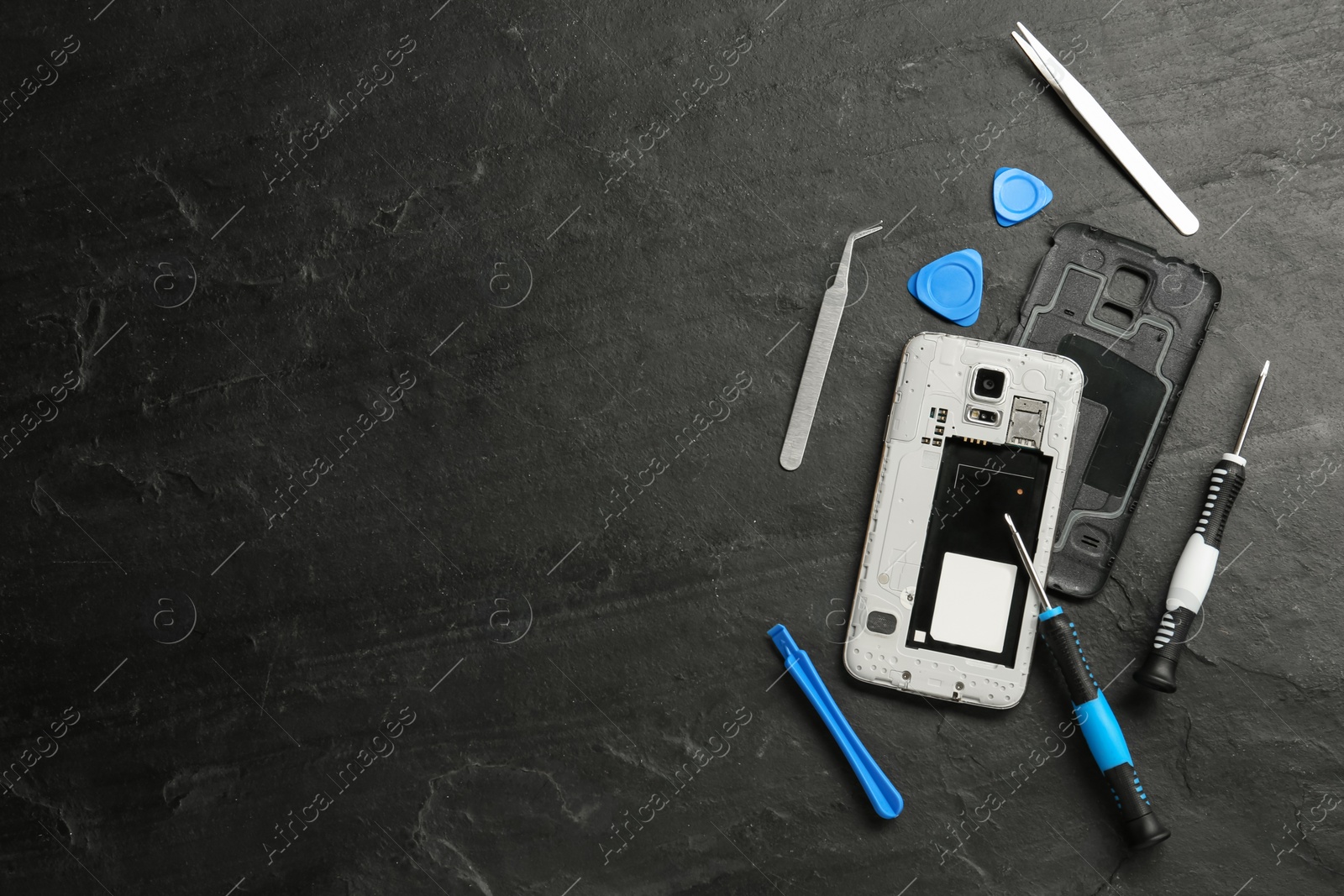 Photo of Damaged smartphone and repair tools on black background, flat lay. Space for text