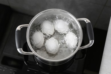 Photo of Chicken eggs boiling in pot on electric stove, above view