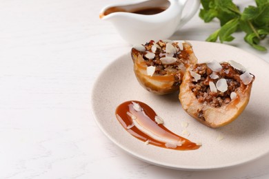 Delicious baked apple halves with nuts and caramel served on white table. Space for text