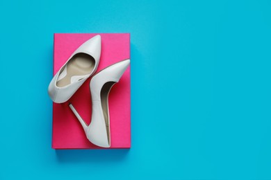 Stylish women's shoes with cardboard box on light blue background, top view. Space for text