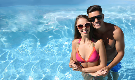 Photo of Happy couple in outdoor pool on sunny summer day. Space for text
