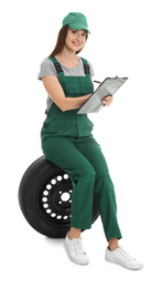 Photo of Professional auto mechanic with wheel and clipboard on white background
