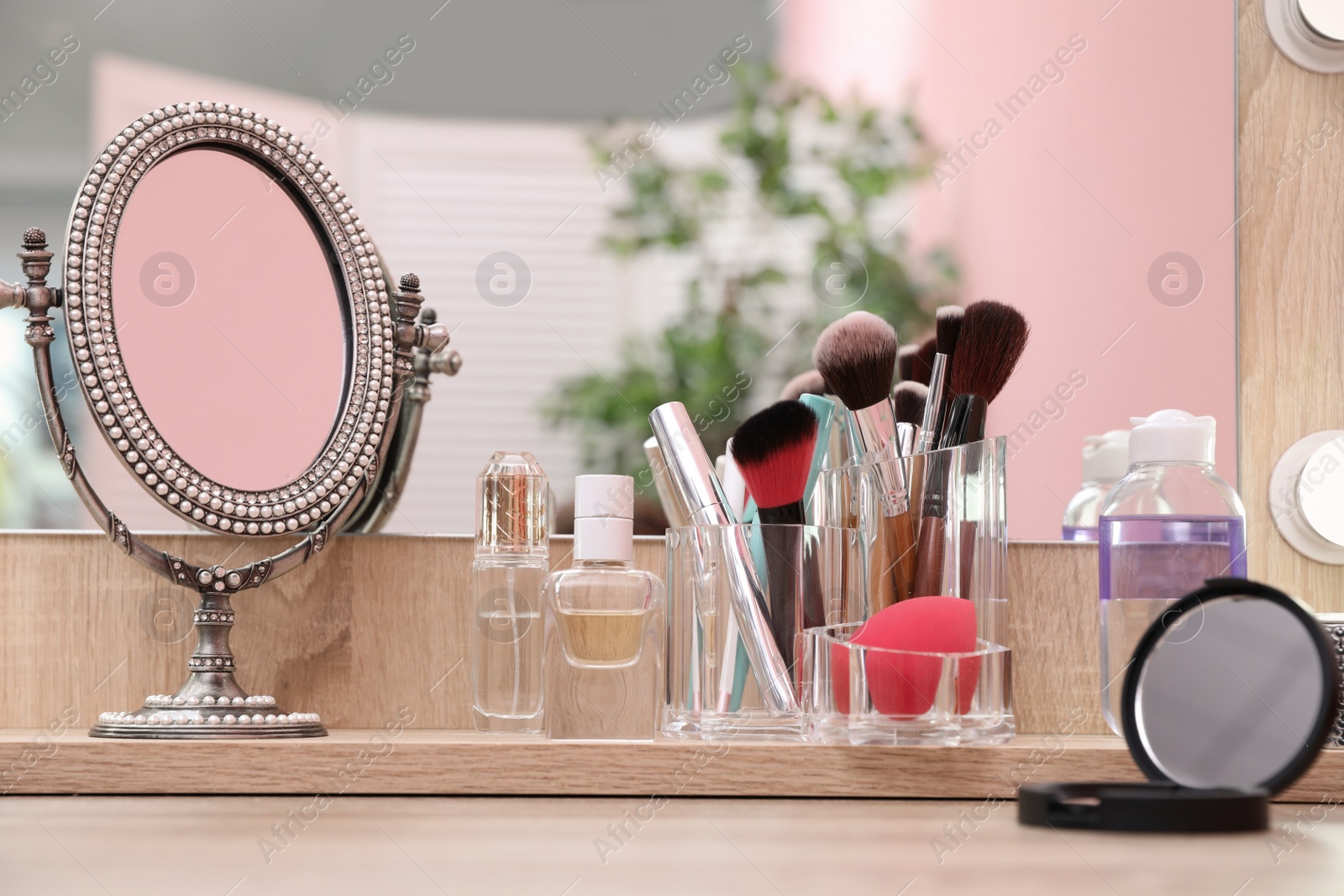 Photo of Organizer with cosmetic products for makeup on table near mirror