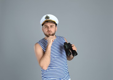 Photo of Thoughtful sailor with binoculars on light grey background