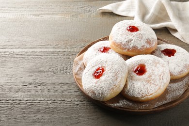 Photo of Delicious donuts with jelly and powdered sugar on wooden table. Space for text