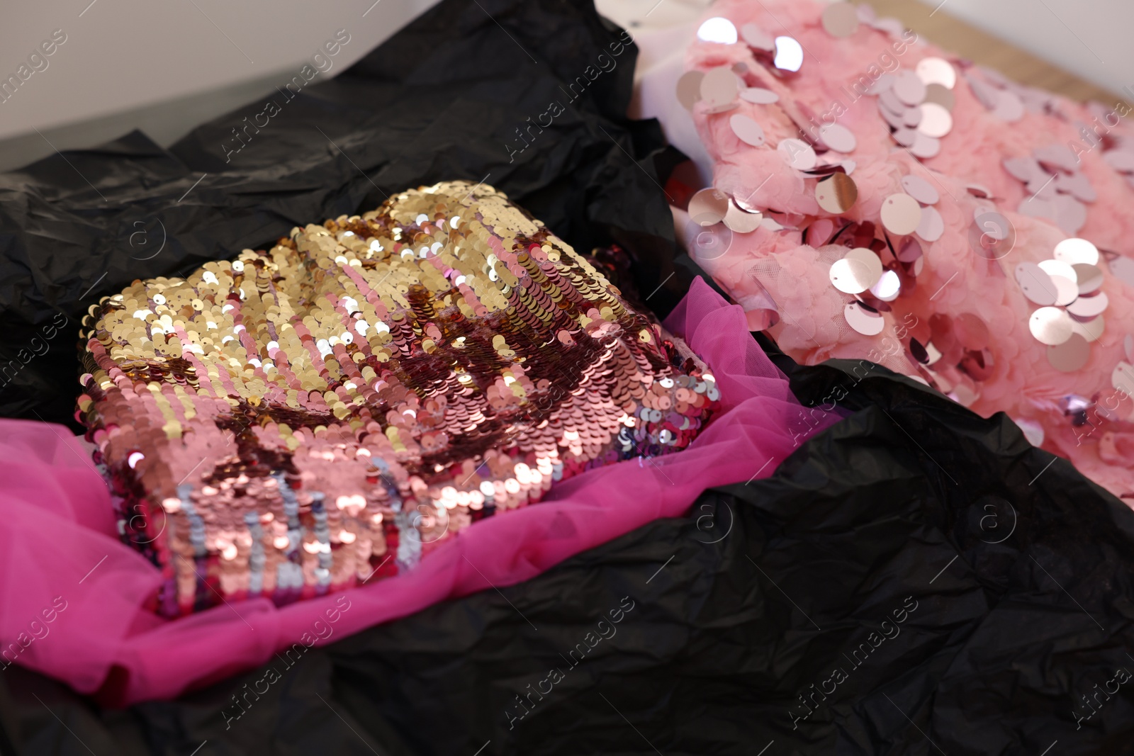 Photo of Stylish pink carnival costume with sequins in black box, closeup