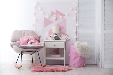 Photo of Rocking chair and nightstand in baby room interior