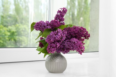 Photo of Beautiful lilac flowers in vase on windowsill