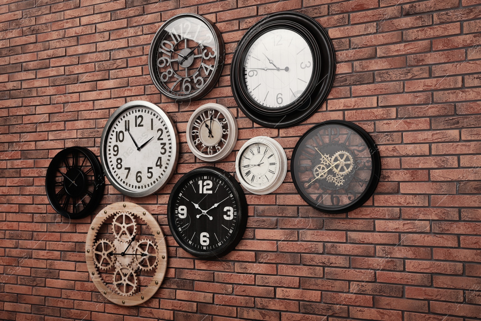 Photo of Collection of clocks hanging on red brick wall