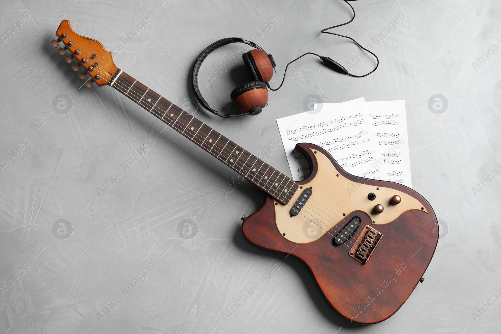 Photo of Modern electric guitar, headphones and music sheets on color background, top view