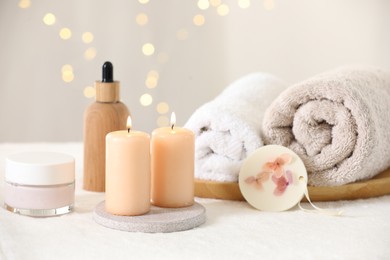 Photo of Spa composition. Burning candles and personal care products on soft white surface