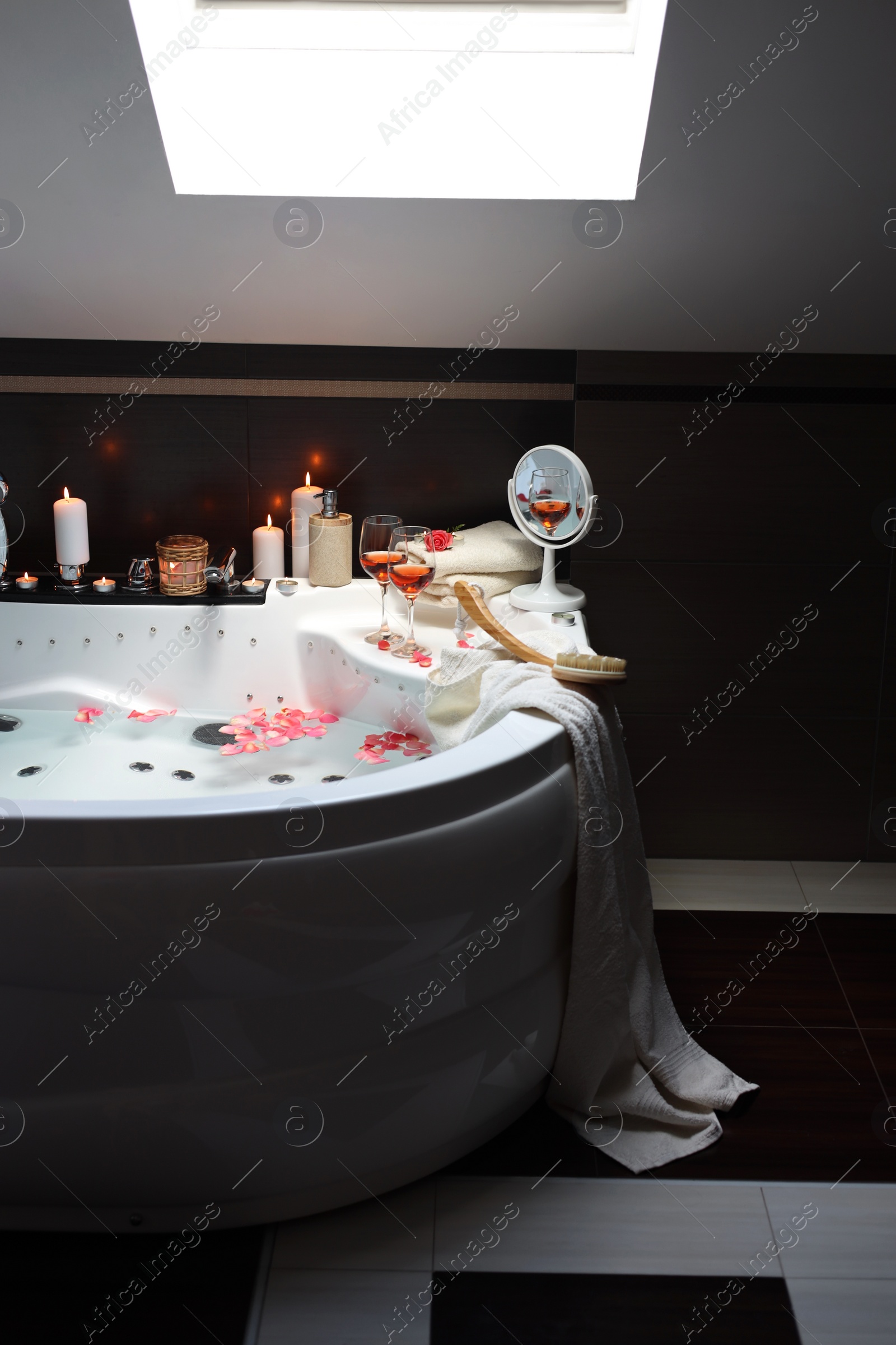 Photo of Bathtub with glasses of wine and candles indoors. Romantic atmosphere