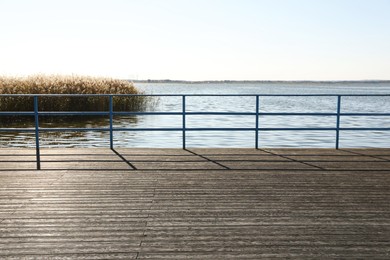 Photo of Beautiful view of wooden terrace with railing near river on sunny day