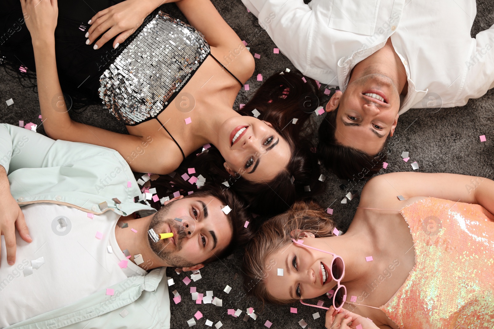 Photo of Group of friends lying on messy floor after party, top view